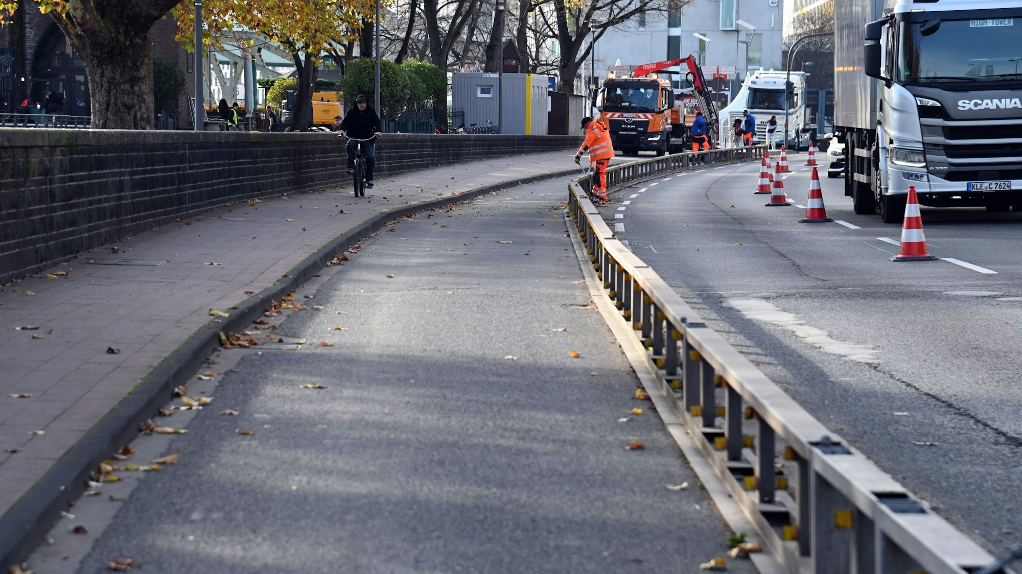 Arbeiter bauen einen Radweg auf einer Straße ab.