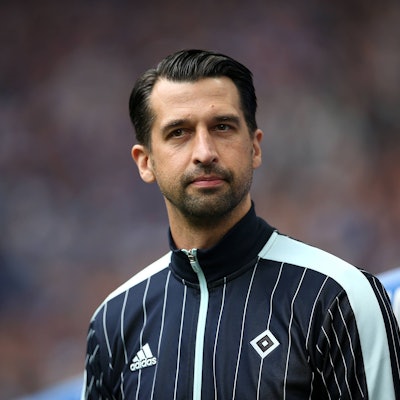 Jonas Boldt steht in HSV-Jacke vor der Bank