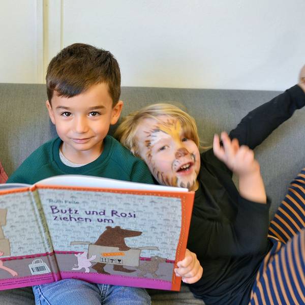 Drei Kinder schauen sich in der Kita „Wirbelwind“ ein Bilderbuch an.