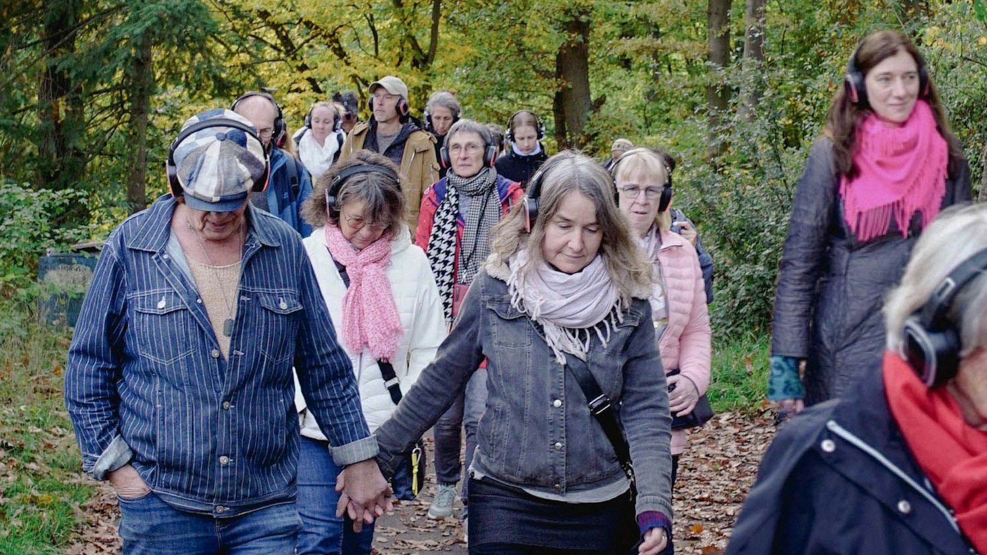 Auf einem Weg an der Steinbachtalsperre laufen Menschen, die alle einen Funkkopfhörer tragen.