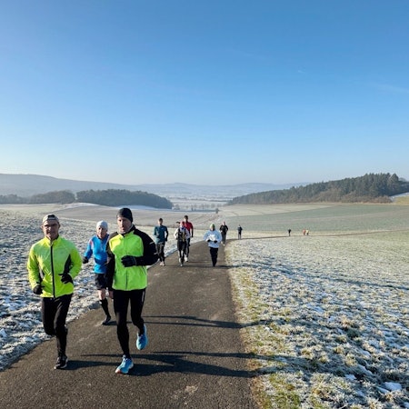 Läufen laufen im Winter über einen Feldweg, auf dem Boden ist Frost.