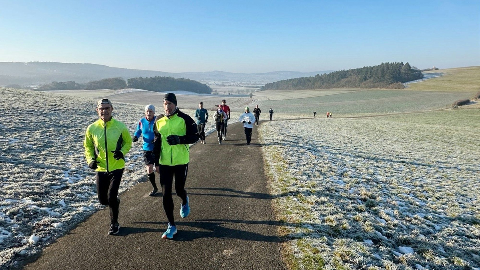 Läufen laufen im Winter über einen Feldweg, auf dem Boden ist Frost.