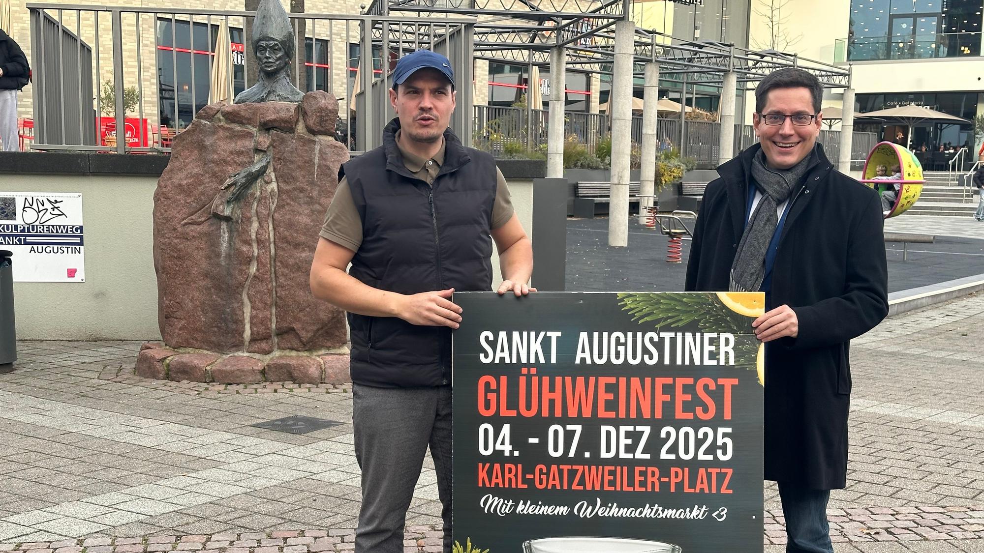 Die Statue des Heiligen Augustinus von Hippo im Hintergrund: Organisator Johannes Radschinski (.) und Burmeister Max Leitterstorf mit dem Plakat des Weinfestes.