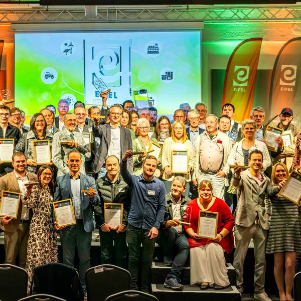 Zahlreiche Menschen stehen auf der Bühne in der Feuerhalle der Alten Tuchfabrik in Euskirchen. Die meisten halten gerahmte Urkunden in den Händen.