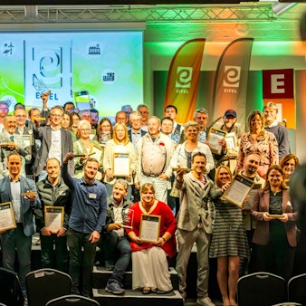 Zahlreiche Menschen stehen auf der Bühne in der Feuerhalle der Alten Tuchfabrik in Euskirchen. Die meisten halten gerahmte Urkunden in den Händen.