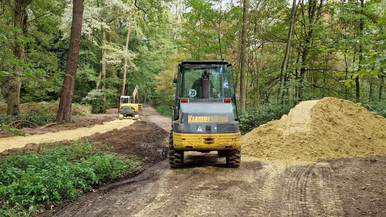 Ein Bagger steht neben einem Sandhaufen.