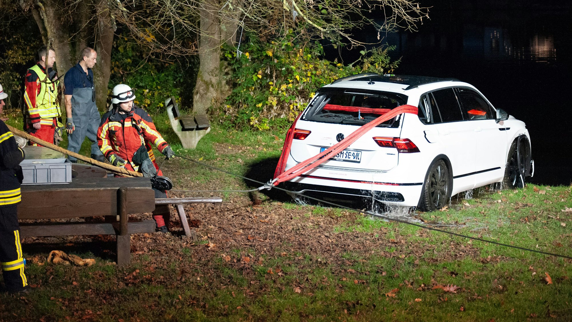 Ein mit Zuggurten umspanntes Auto am Ufer.