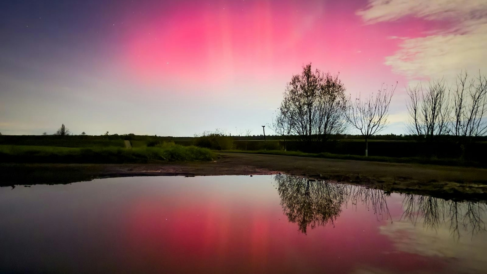 Buntes Licht am Horizont spiegelt sich in einem Gewässer.