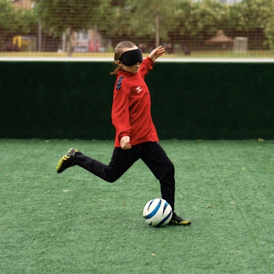 Zu sehen ist ein junger Blindenfußballer, der vor den Ball tritt.