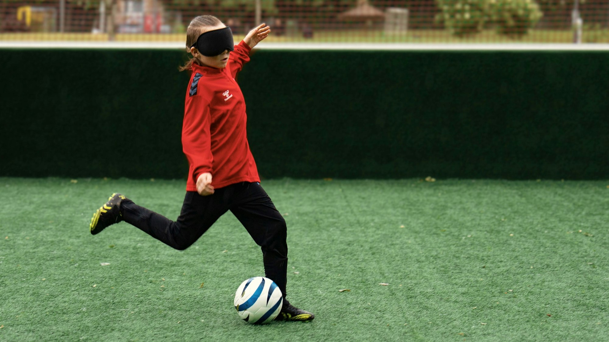 Zu sehen ist ein junger Blindenfußballer, der vor den Ball tritt.