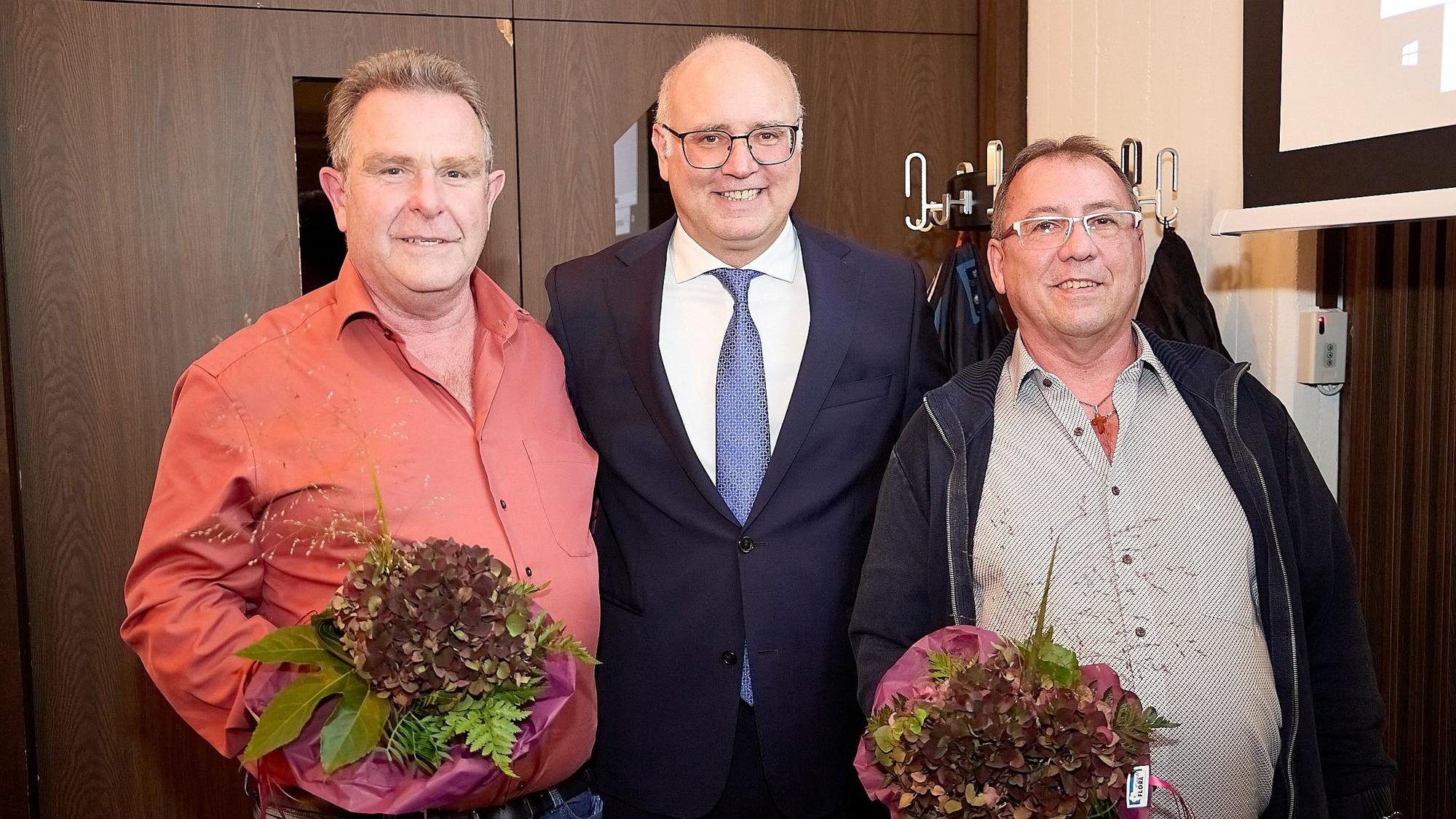 Werner Bongard, Jochen Weiler und Hans-Paul Kruppert stehen nebeneinander. Bongard und Kruppert haben jeweils einen Blumenstrauß in der Hand.