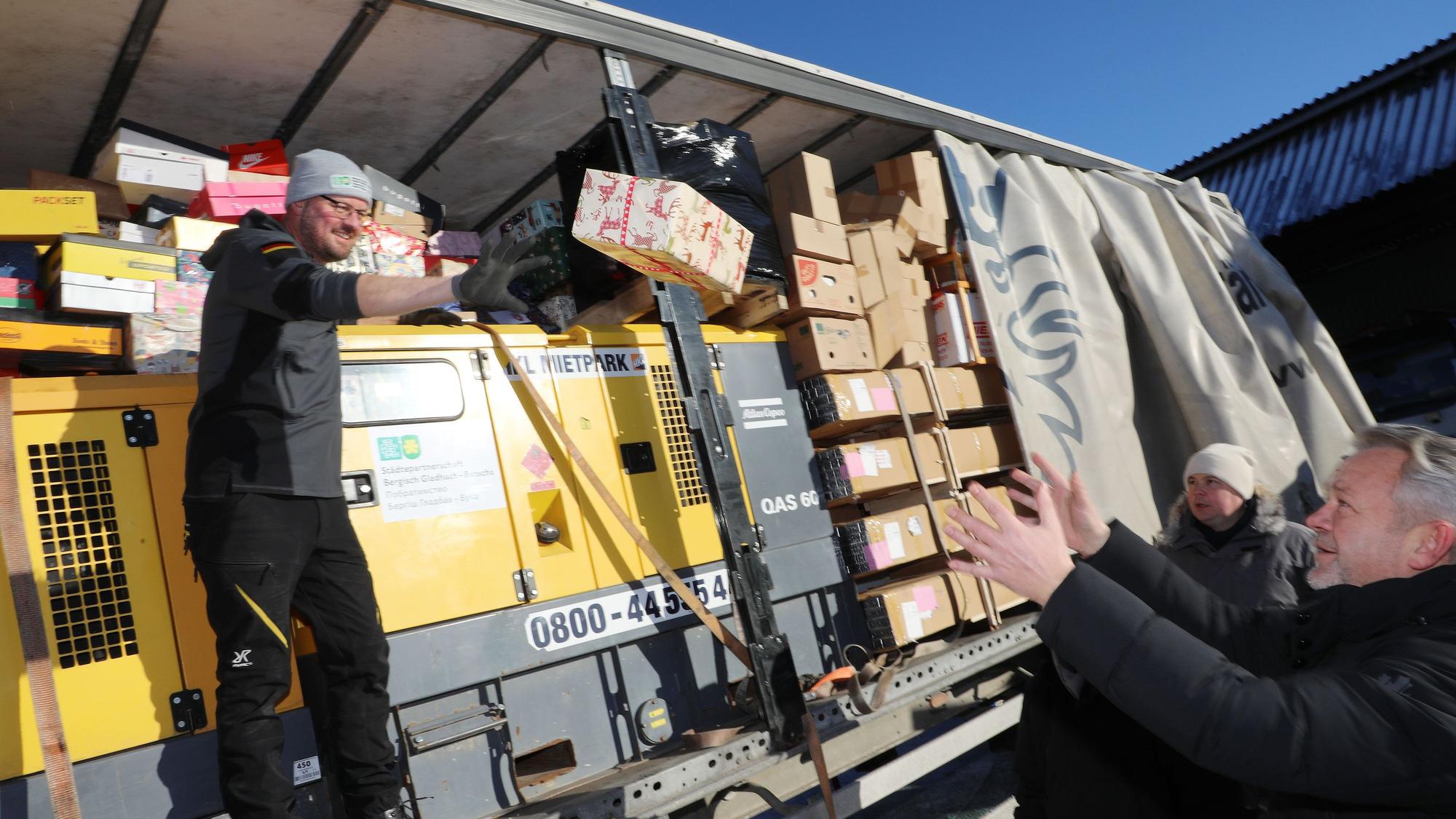 Ehrenamtler geben vom Wagen aus die Geschenke weiter.