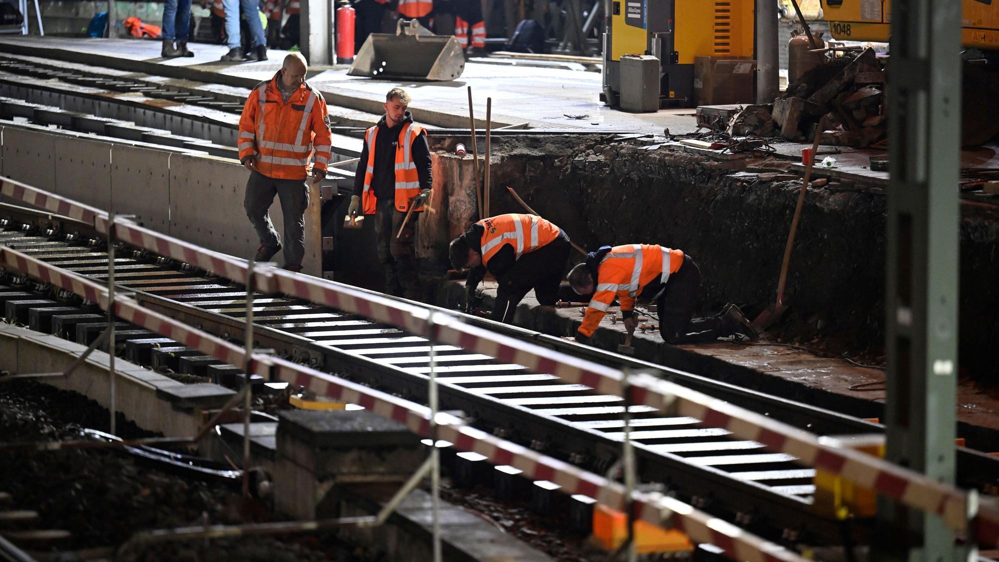 Arbeiter der Deutschen Bahn arbeiten im menschenleeren Hauptbahnhof Köln an Gleisen.