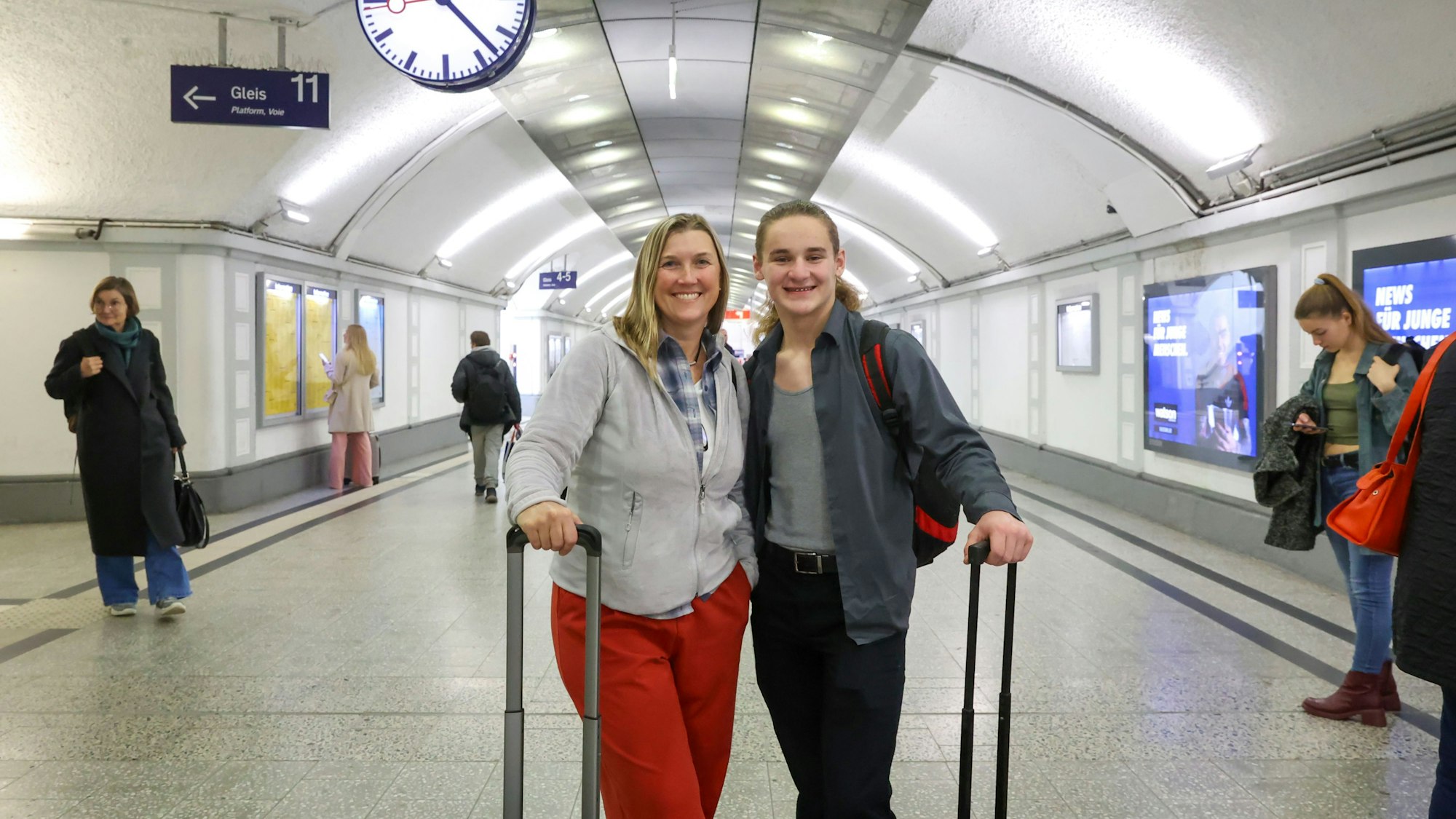 Eine Frau und ein junger Mann stehen mit Koffern im Deutzer Bahnhof.