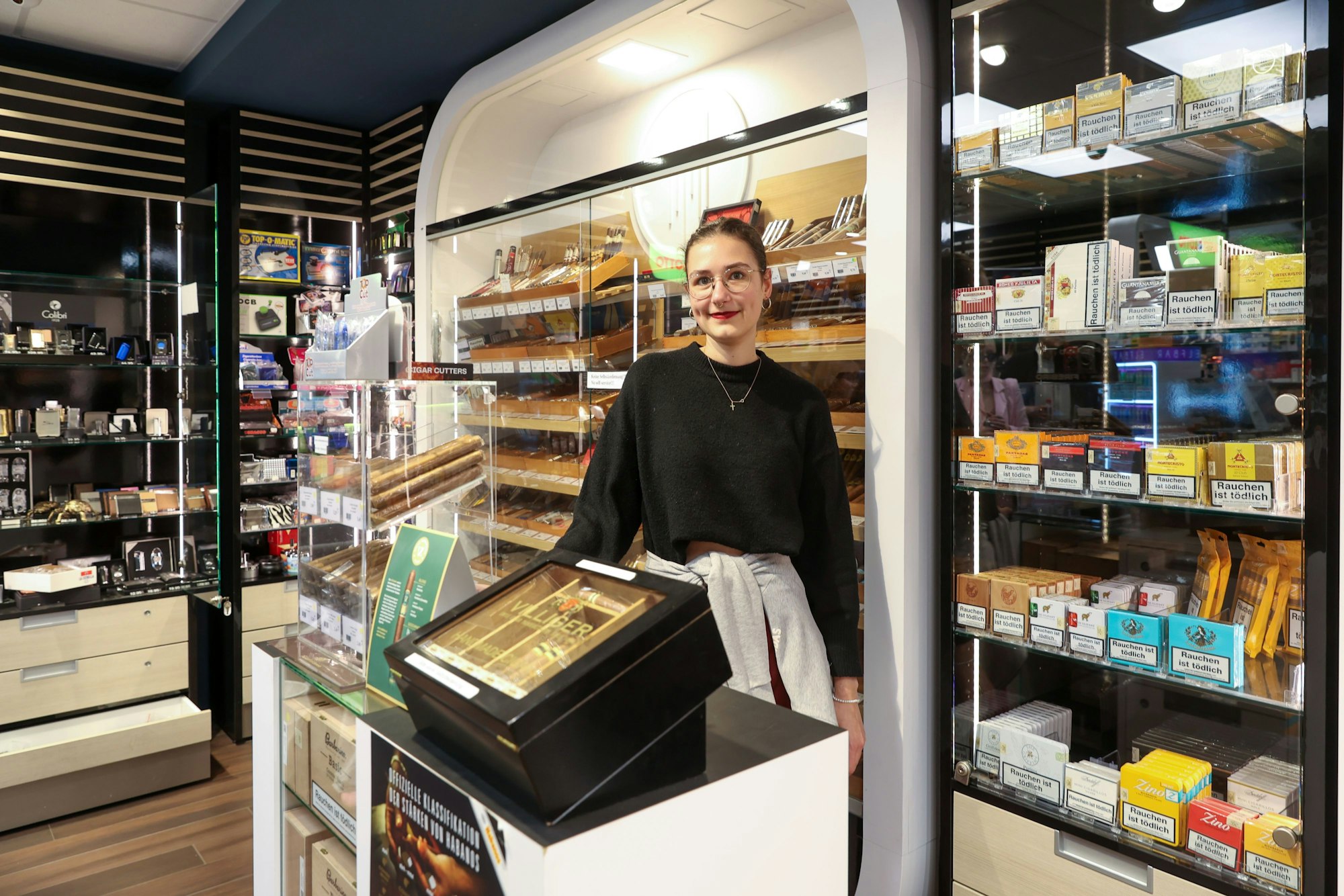 Eine junge Frau steht hinter der Theke in einem Tabakfachgeschäft.