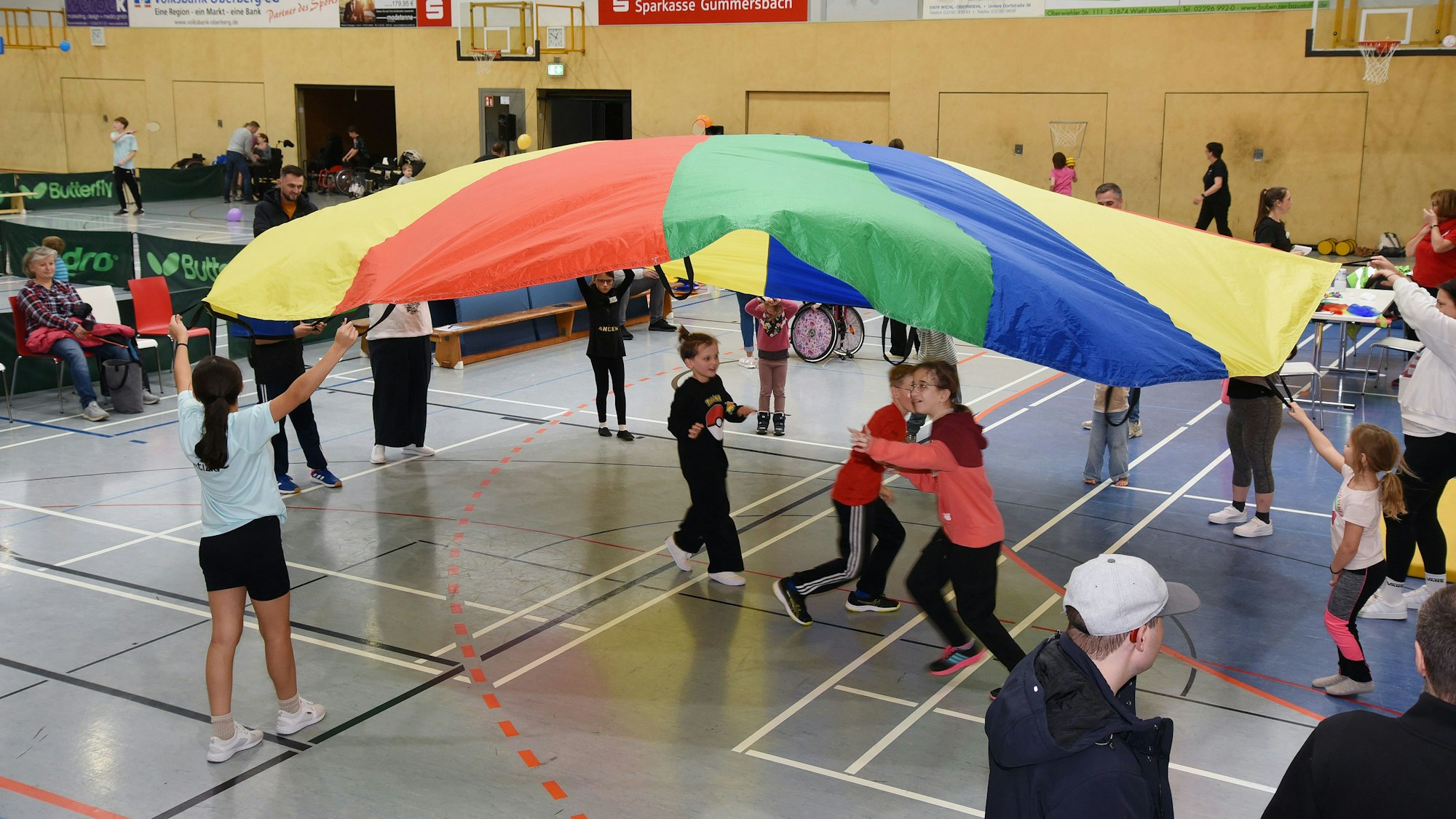Kinder laufen unter einem Schirmtuch umher.