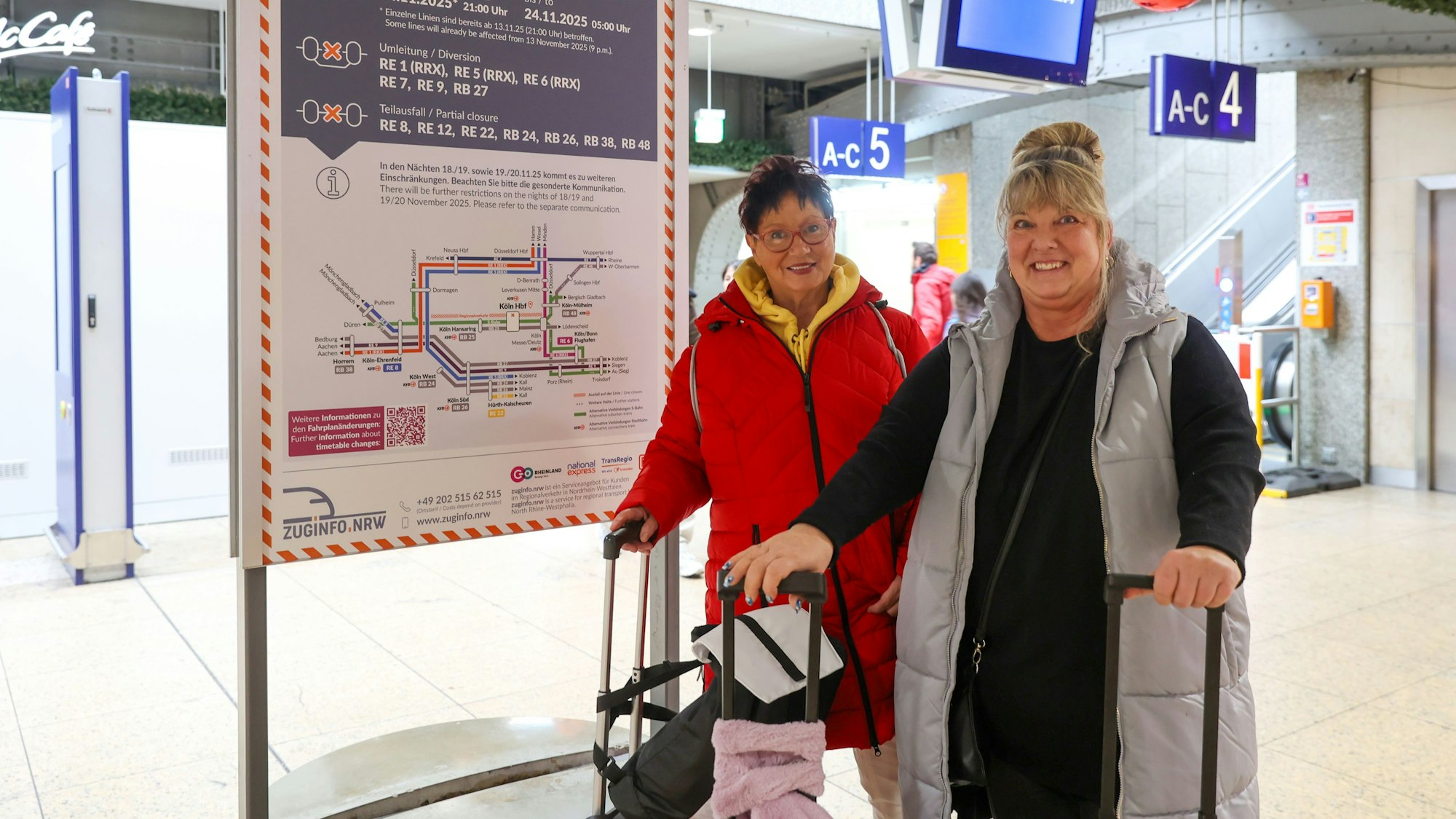 Zwei Frauen stehen mit Koffern im Hauptbahnhof.