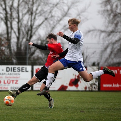 Ein Spieler des FC Dollendorf-Ripsdorf versucht mit einem Sprung an den Ball zu kommen, den ein Spieler von Dreiborn am Fuß hat.