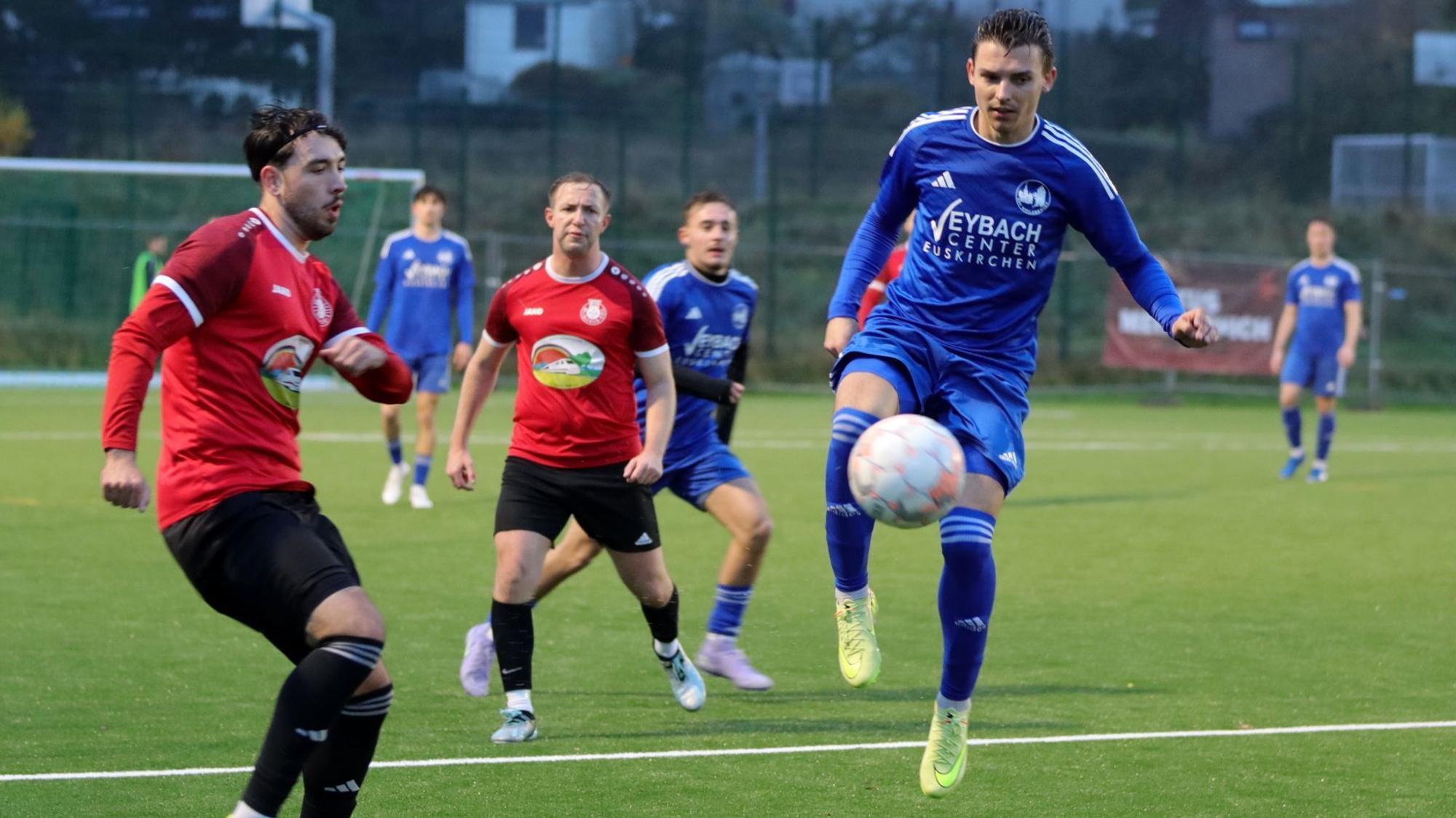 Mike Nandzik von Weilerswist springt in die Luft, der Ball ist vor ihm. Es ist nicht zu erkennen, ob er schießt oder den Ball annimmt. Ein Gegenspieler beobachtet ihn.