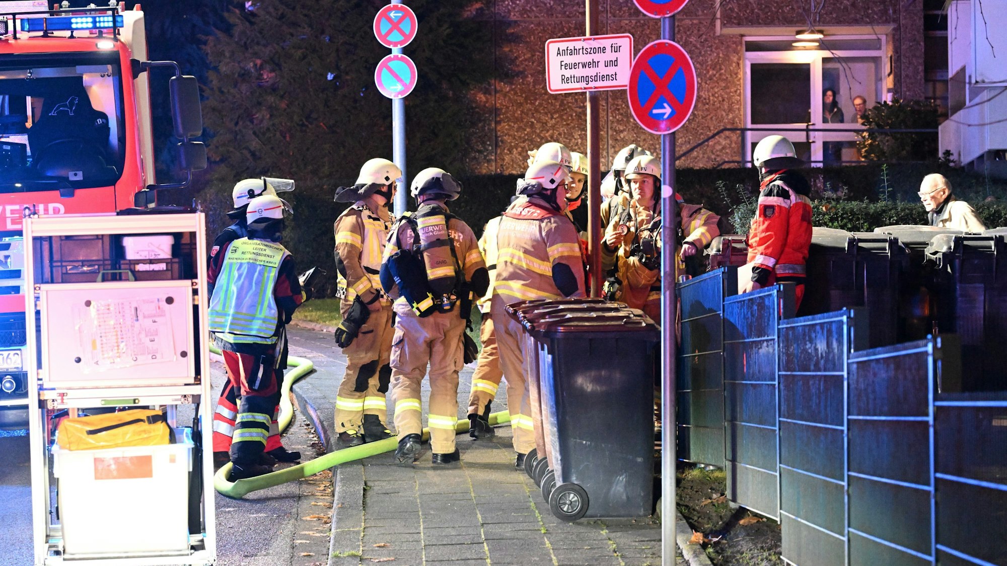 Feuerwehrleute stehen an einem Hauszugang an der Reginharstraße in Bergisch Gladbach-Bensberg.