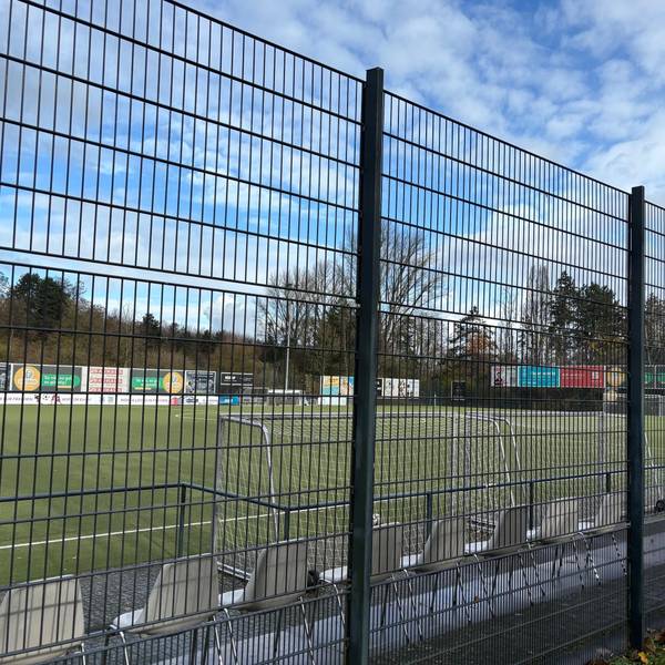 Auf dem Bild ist ein Sportplatz hinter einem Zaun zu sehen.