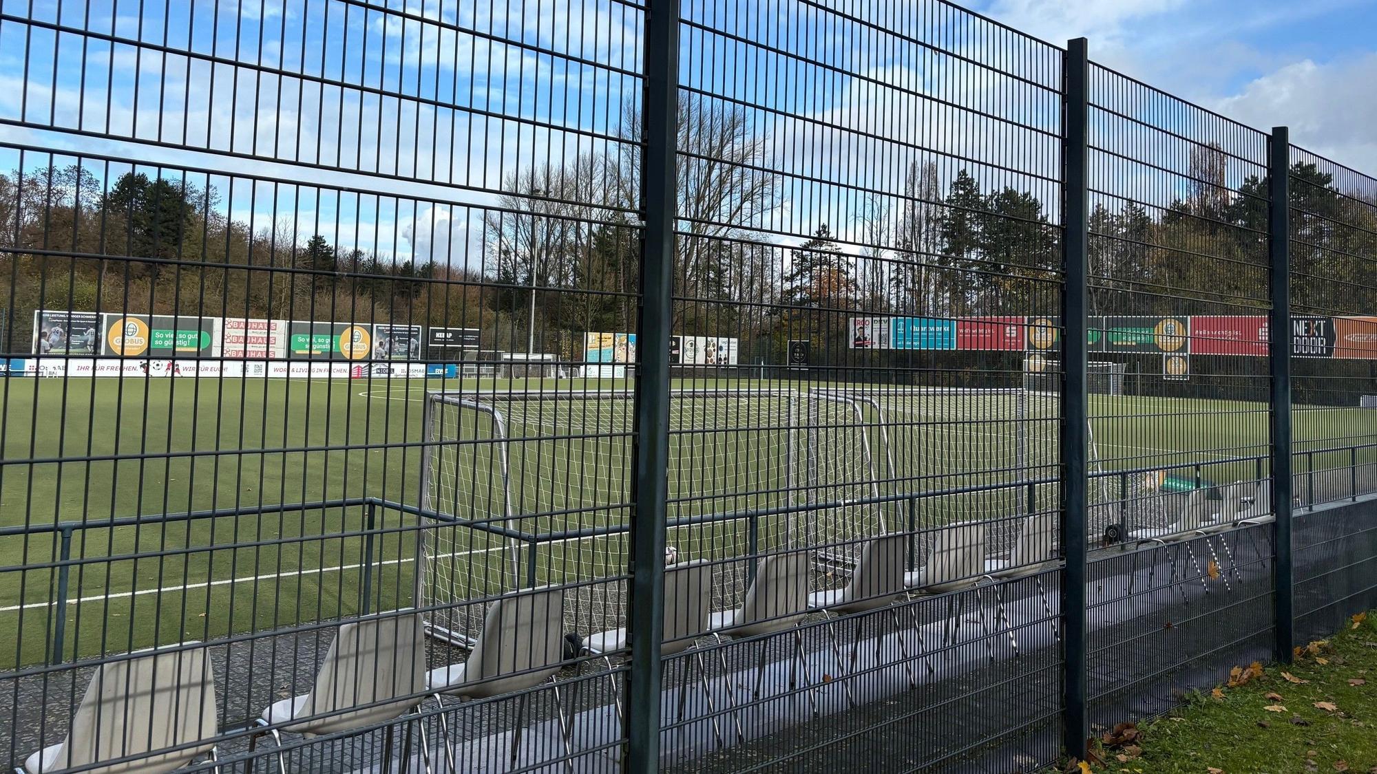 Auf dem Bild ist ein Sportplatz hinter einem Zaun zu sehen.