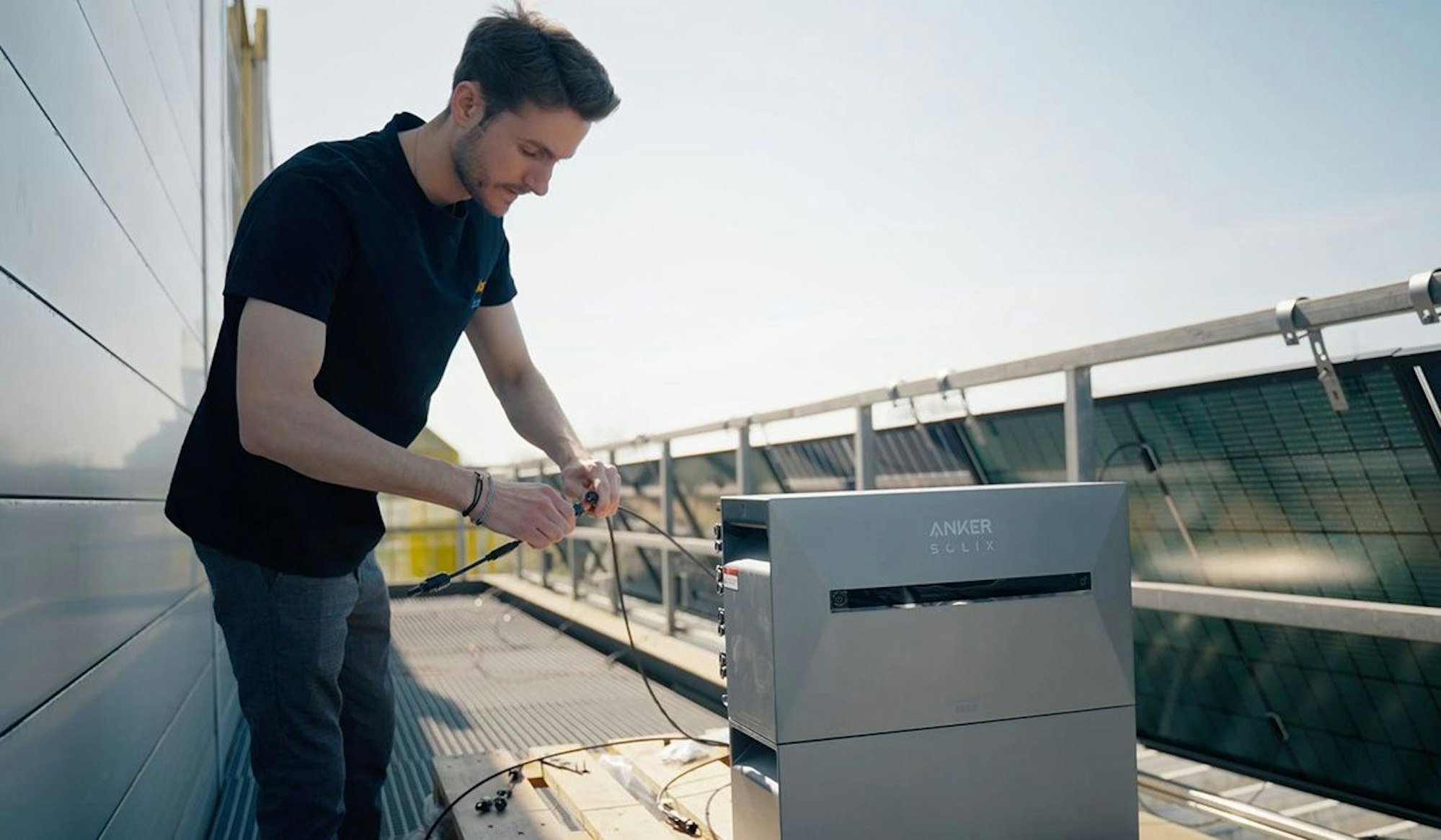 Ein Solago Mitarbeiter installiert eine Anker Solix 3 Pro Solar-Speicherbank an einem bereits installierten Balkonkraftwerk.