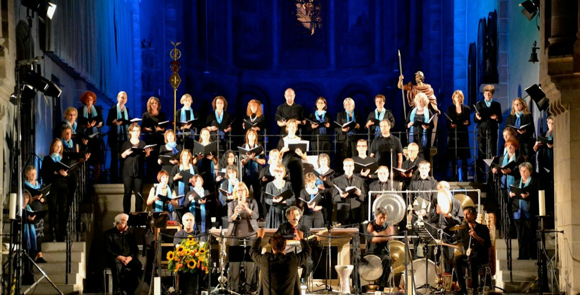 Ein Chor und Orchester sind im Altarraum einer Kirche aufgestellt.