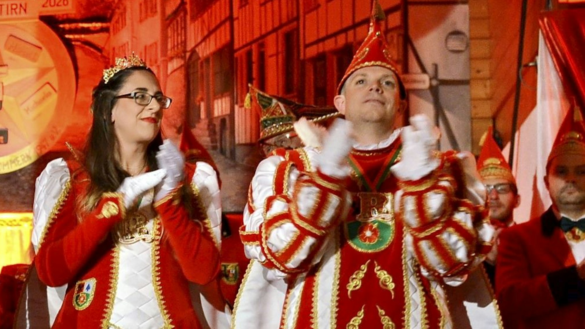 Prinzessin Michaela I. und Prinz Marcel I. stehen im Tollitäten-Ornat klatschend auf der Bühne der Kommerner Bürgerhalle.