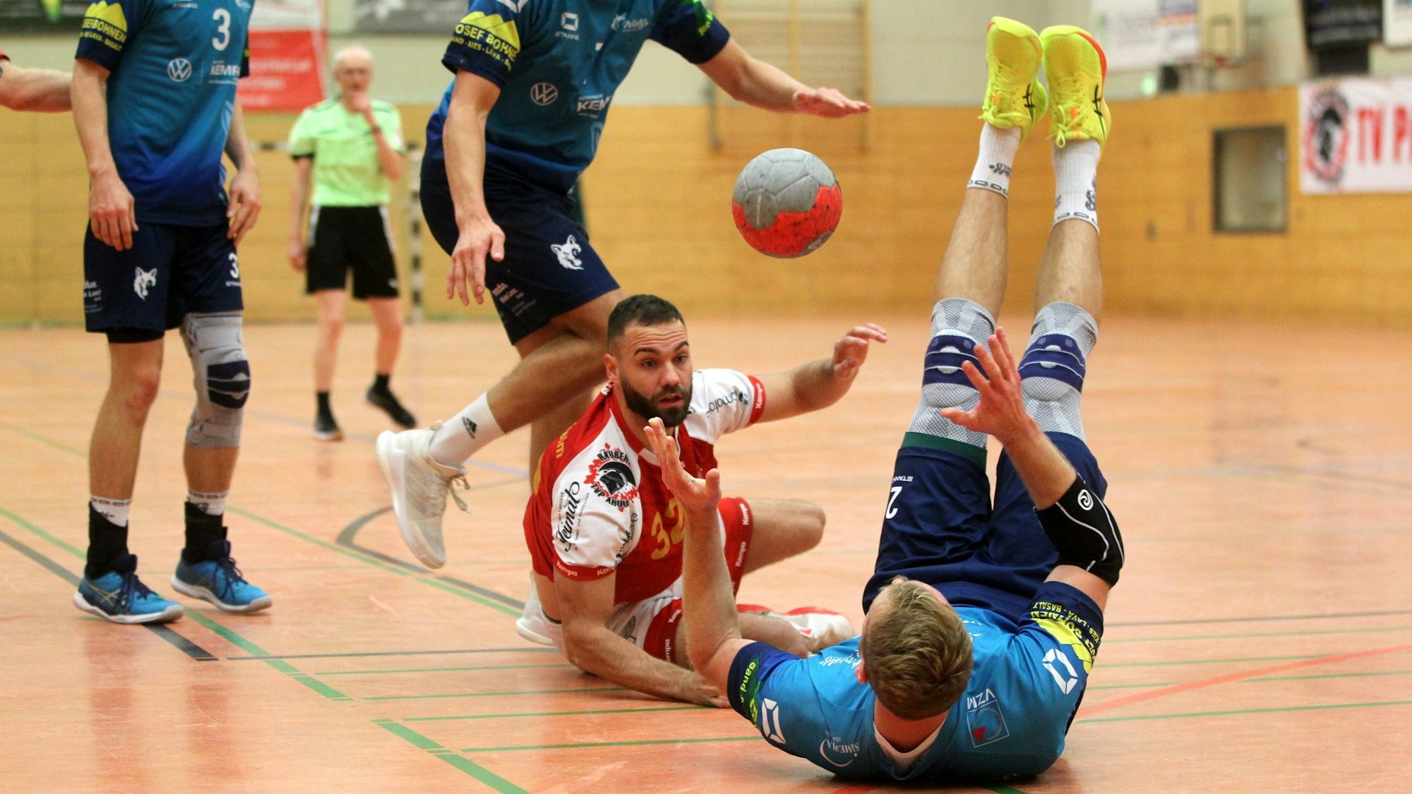 Dennis Schüller liegt halb auf dem Boden und passt, ein Gegenspieler liegt rücklings vor ihm.