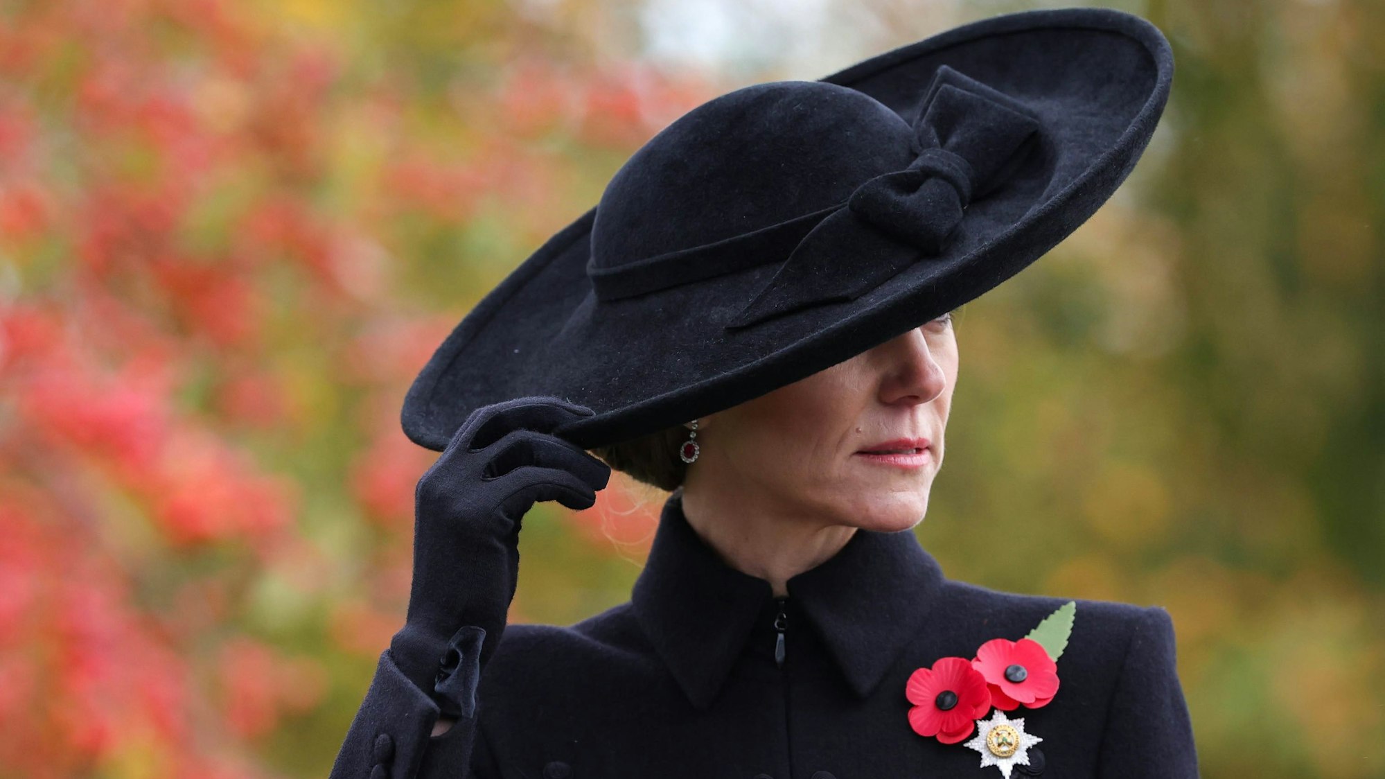 Catherine, Prinzessin von Wales, in schwarzem Mantel und Hut mit Mohnblumen