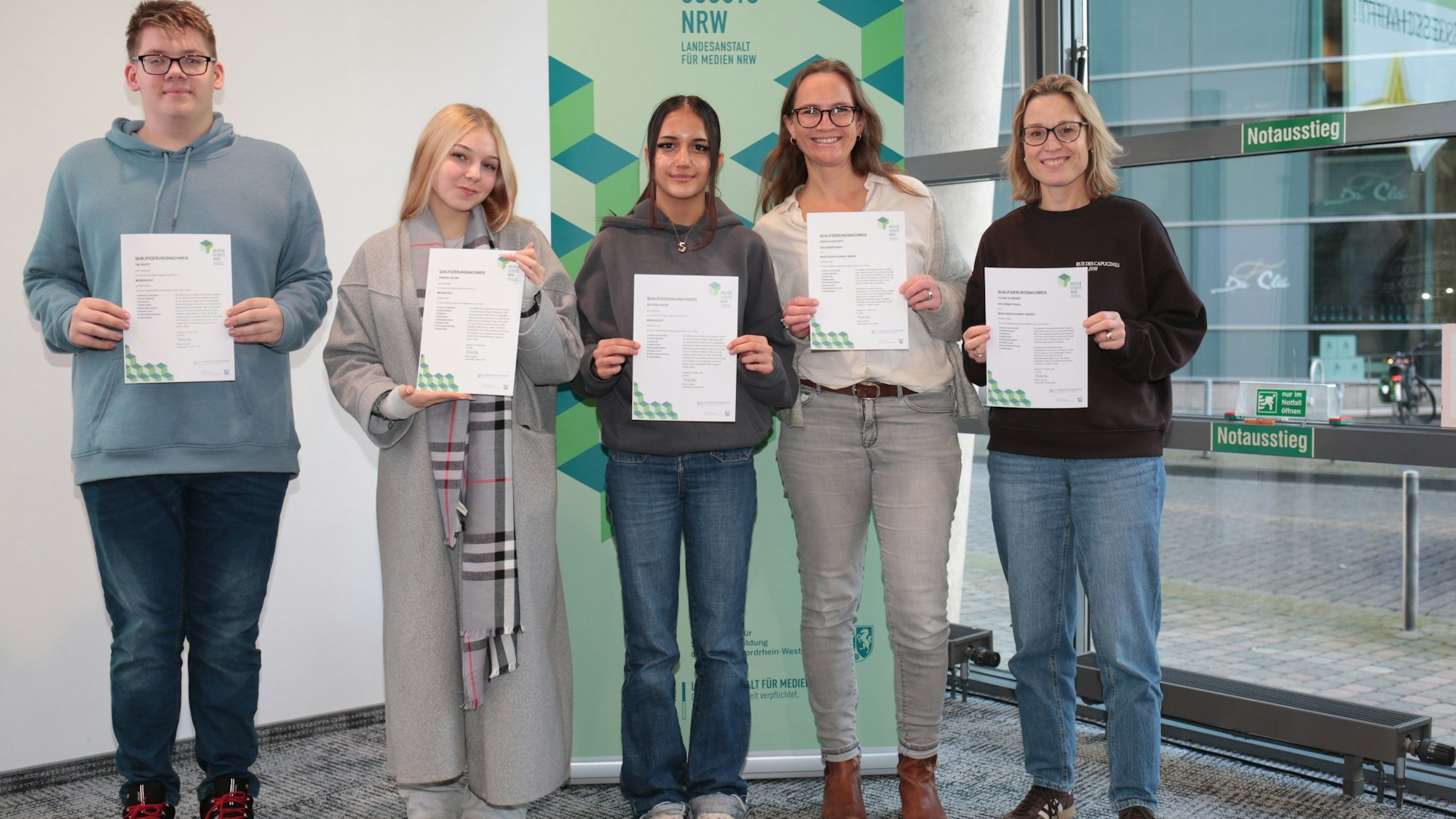 Auf dem Bild sind drei Jugendliche und zwei Frauen zu sehen, die Urkunden in die Kamera halten.