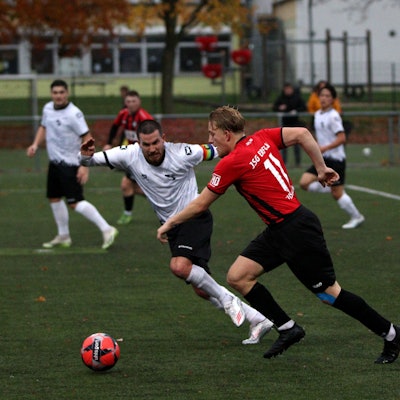 Der Spieler der JSG Erft geht mit Tempo am gegnerischen Kapitän vorbei, der böse guckt.