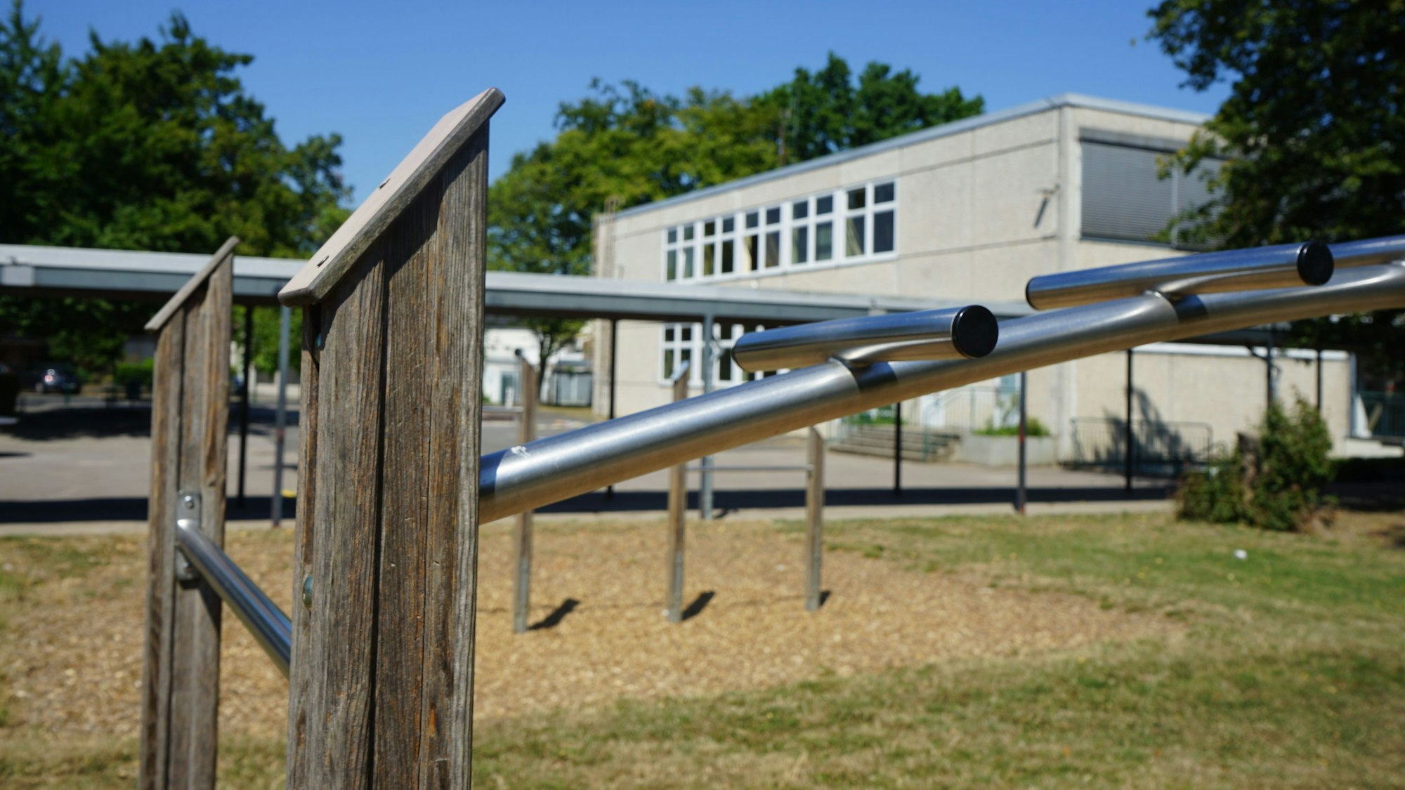 Auf dem Foto ist ein Klettergüst auf dem Schulhof der Hermann-Gmeiner-Schule zu sehen, dahinter das Schulgebäude.