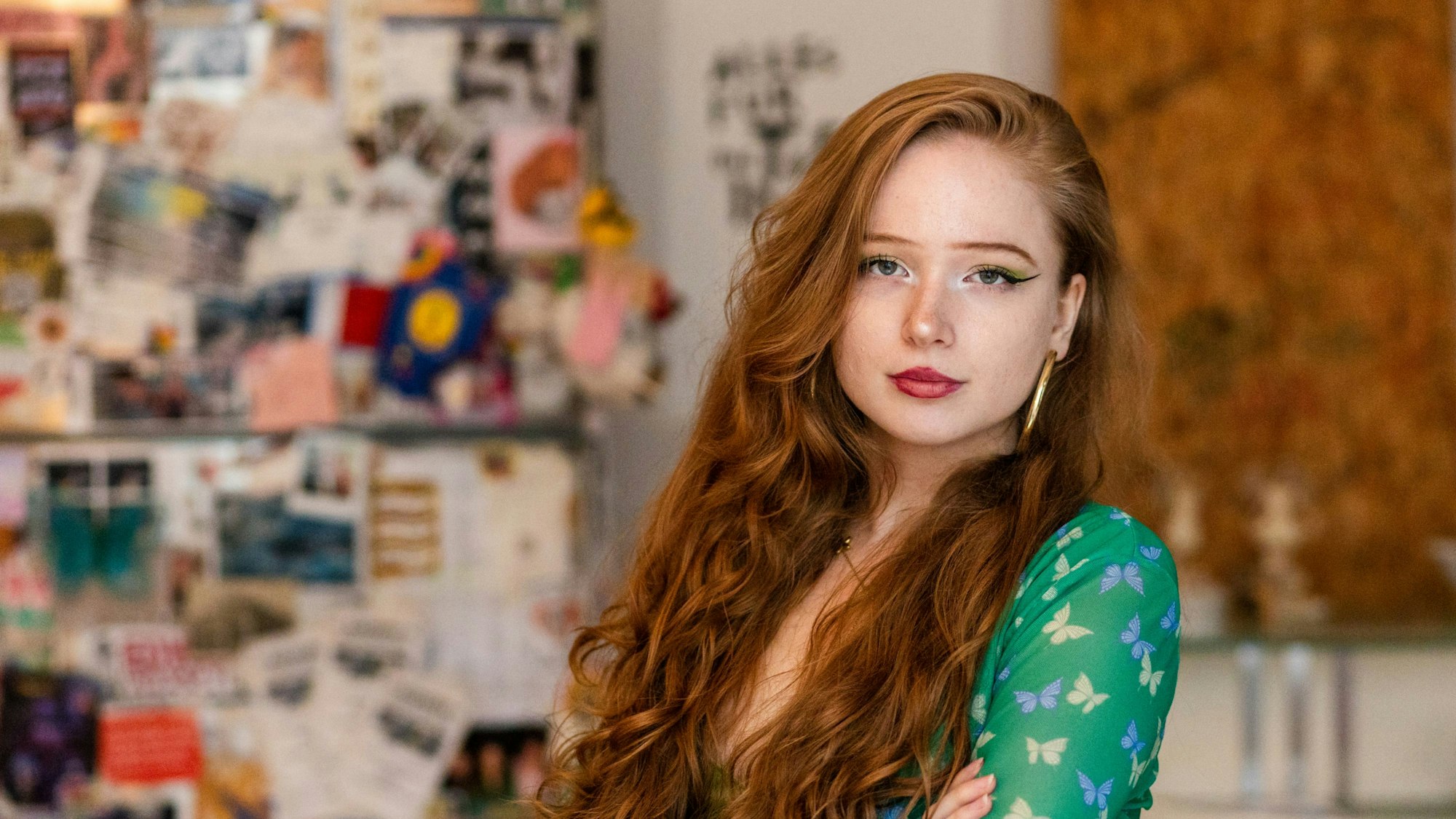 Eine junge Frau mit roten Locken und grünem Kleid schaut in die Kamera.