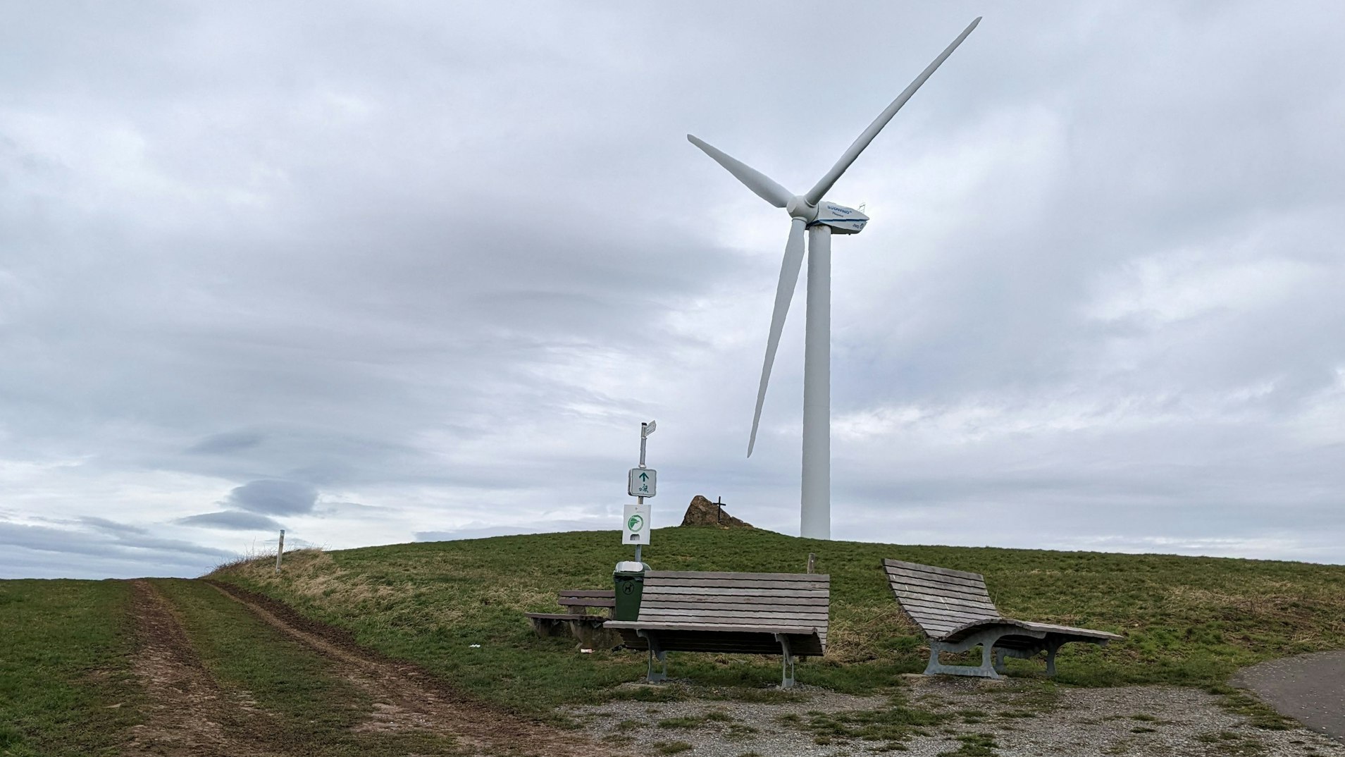Windkraftanlage auf dem Pflugberg bei Lorbach, davor stehen zwei Panorama-Liegen aus Holz.