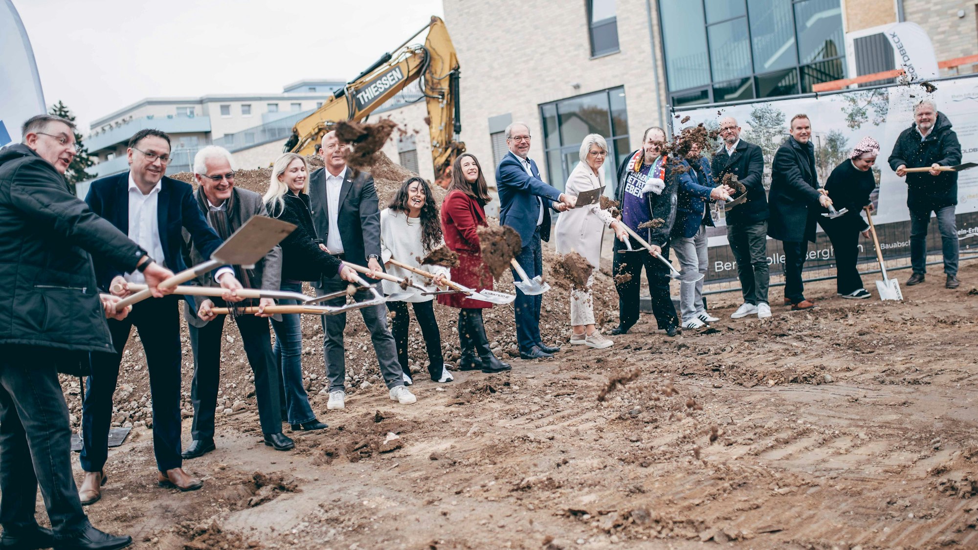 Zu sehen sind zahlreiche Frauen und Männer mit Spaten auf einer Baustelle.
