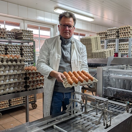 Das Foto zeigt den Landwirt mit einer Palette voller Eier an der Sortier- und Verpackungsanlage.