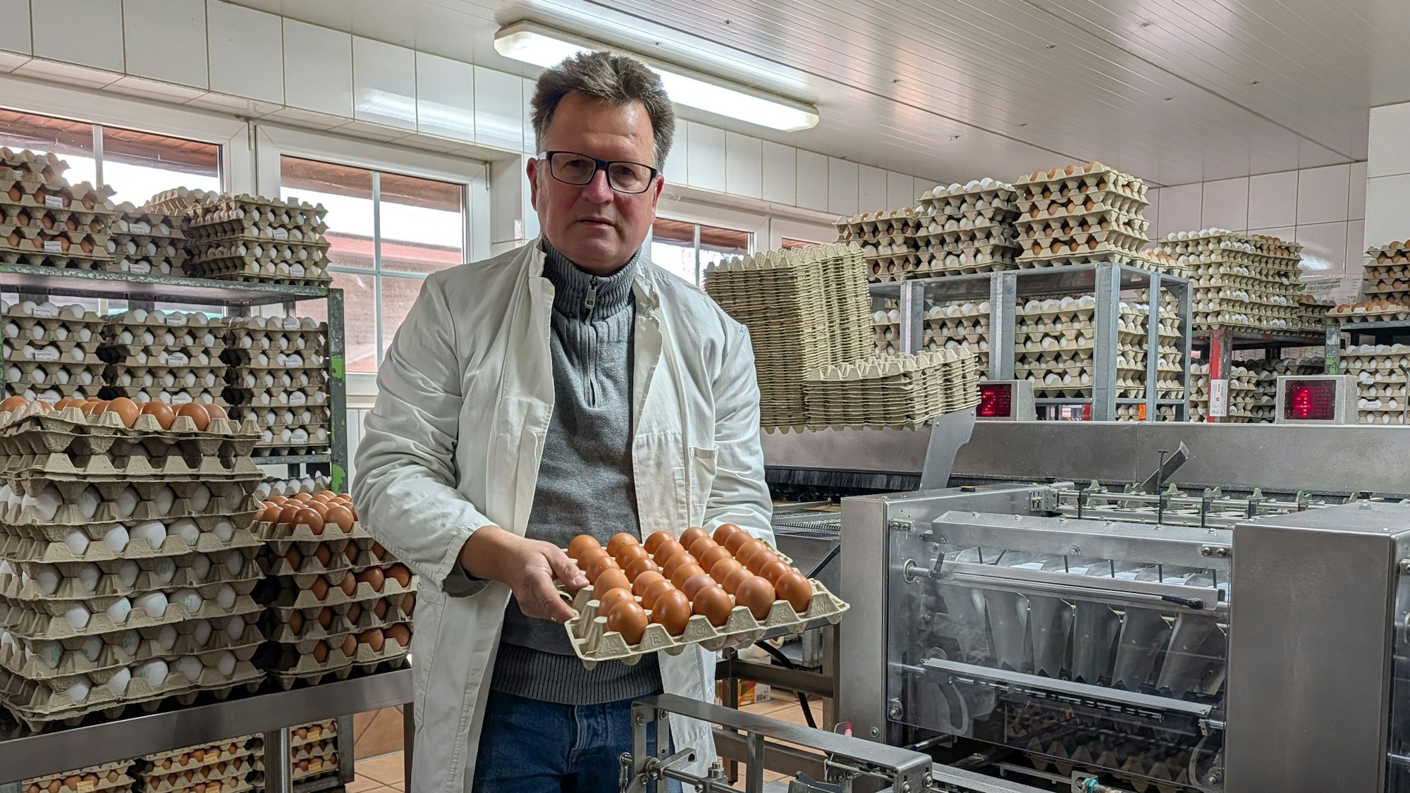 Das Foto zeigt den Landwirt mit einer Palette voller Eier an der Sortier- und Verpackungsanlage.