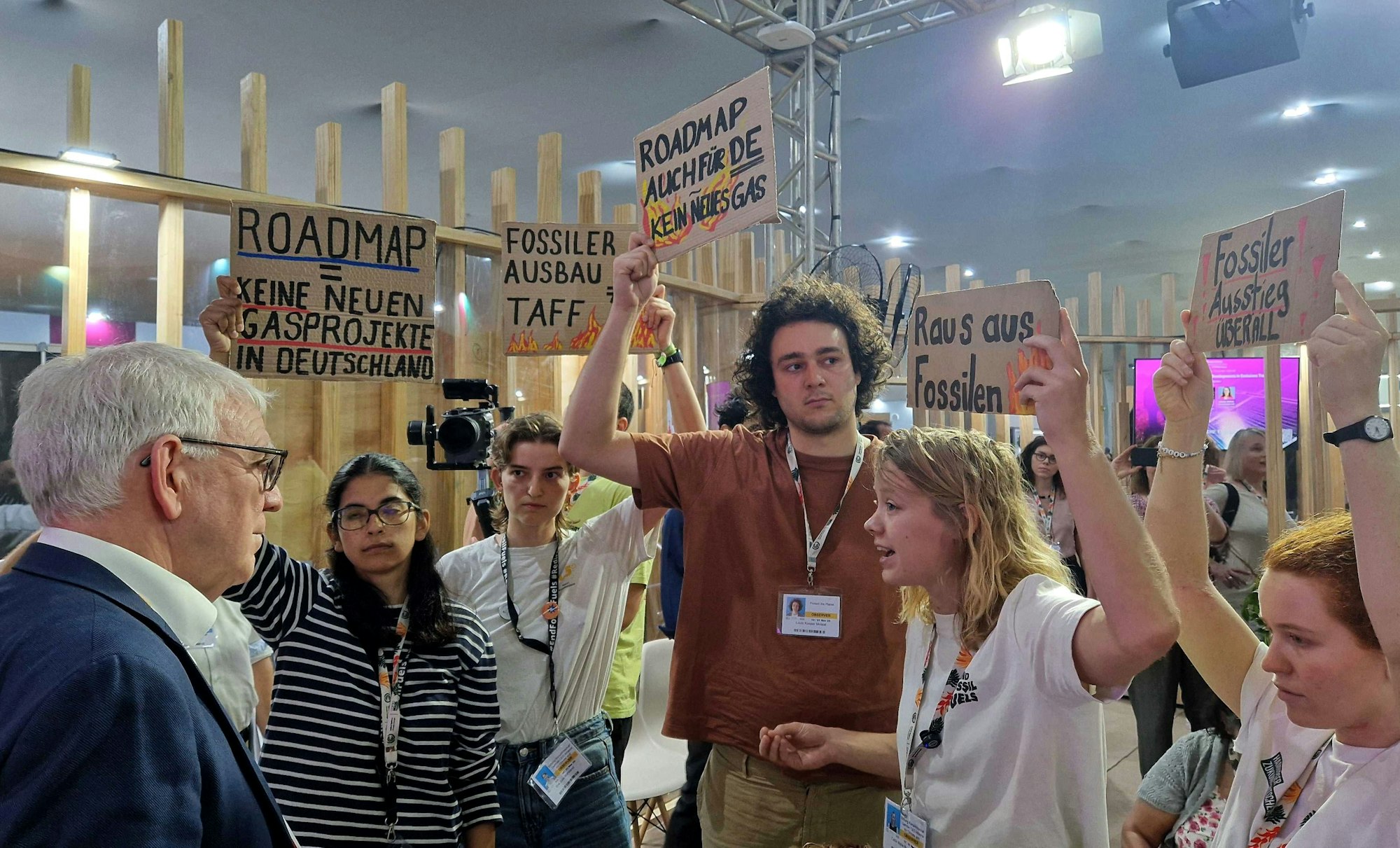 Das Bild zeigt Aktivisten von Fridays for Future, die Jochen Flasbarth (SPD, l), Staatssekretär im Bundesministerium für Umwelt, Klimaschutz, Naturschutz und nukleare Sicherheit, im Deutschen Pavillon auf der Weltklimakonferenz COP30 gegenüber stehen. Foto: Larissa Schwedes/dpa