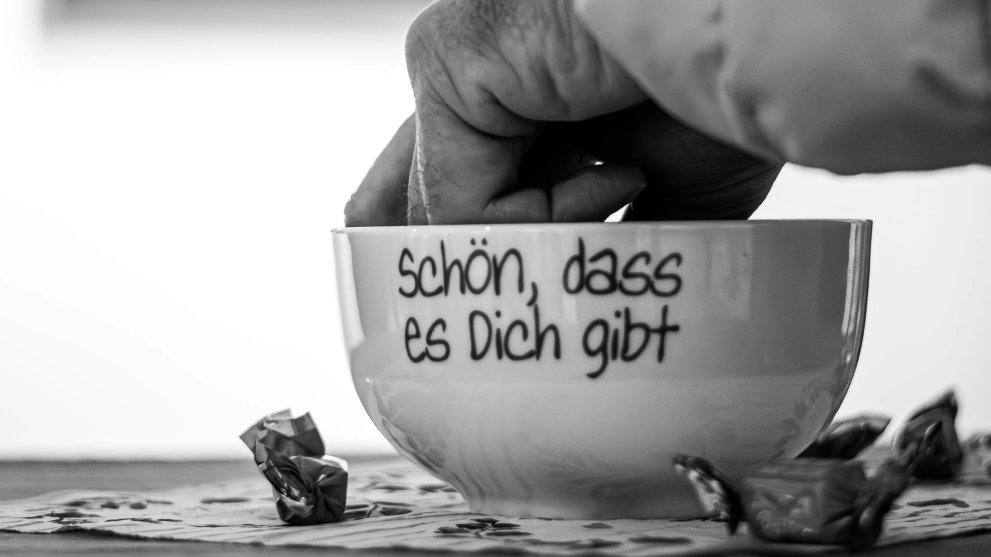 Eine Hand greift in eine Schale mit der Aufschrift „Schön, dass es Dich gibt“.