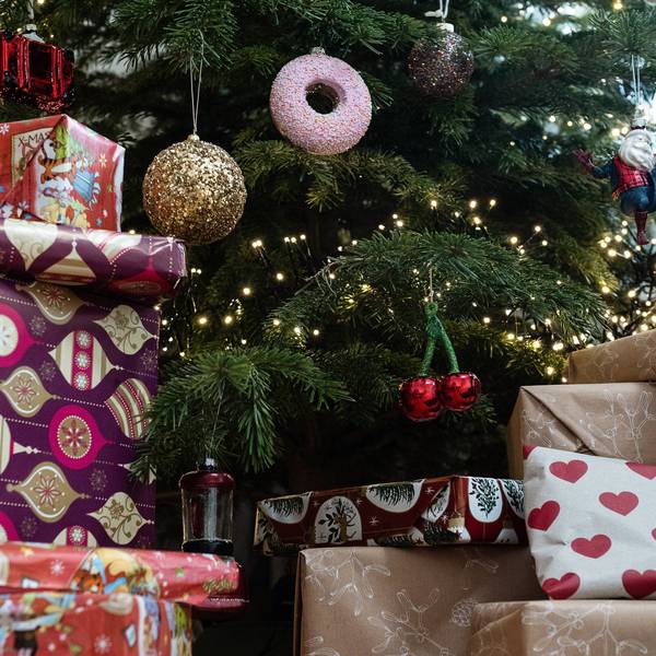 Eingepackte Geschenke liegen unter einem geschmückten Weihnachtsbaum.