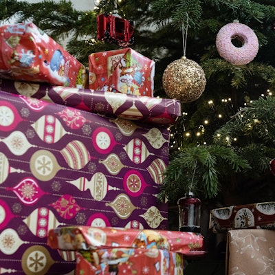 Eingepackte Geschenke liegen unter einem geschmückten Weihnachtsbaum.