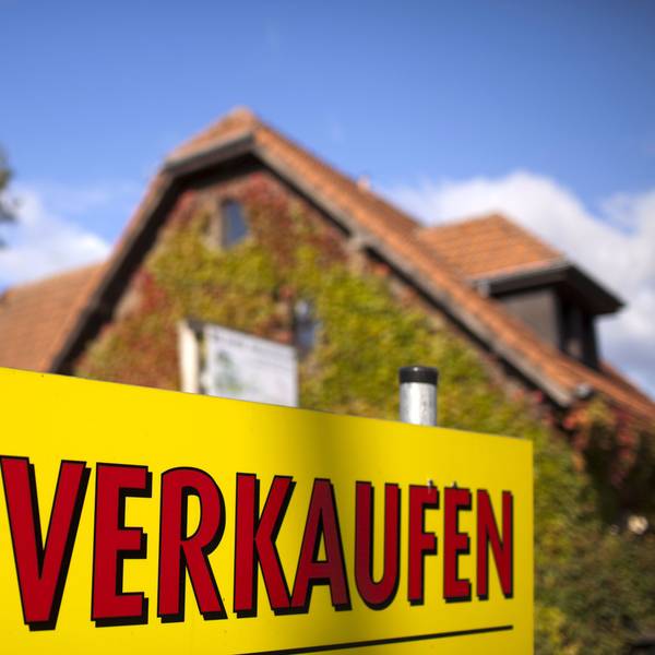 Ein Schild "Zu verkaufen" steht vor einem Haus