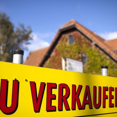 Ein Schild "Zu verkaufen" steht vor einem Haus