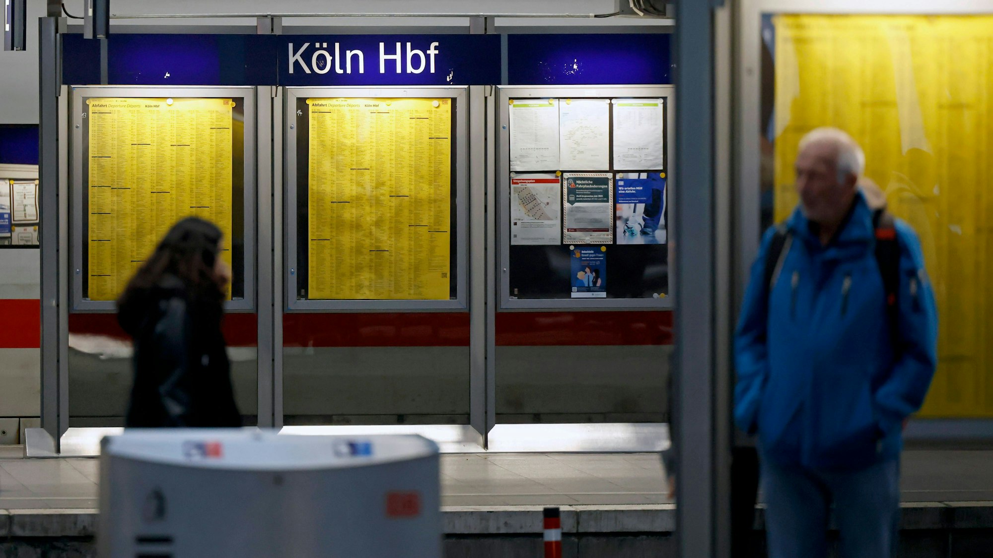 Das Bild zeigt Menschen, die am Kölner Hauptbahnhof vor den Anzeigetafeln stehen.