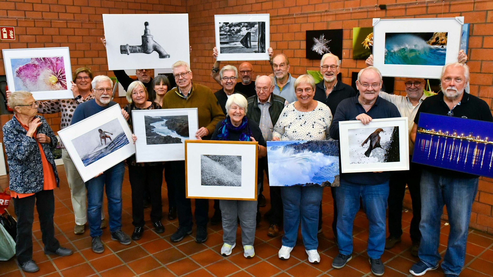Zu sehen sind Frauen und Männer, die gerahmte Fotos halten.