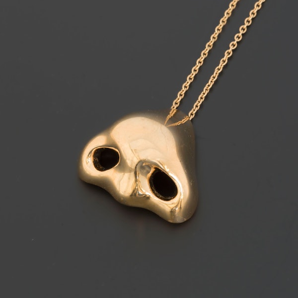 Eine goldene Nase hängt an einer Kette.