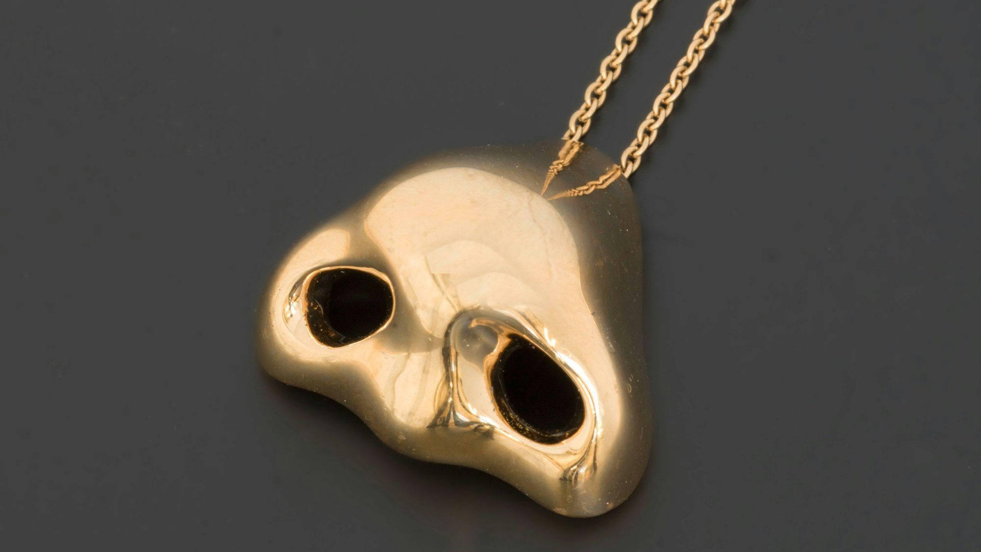 Eine goldene Nase hängt an einer Kette.