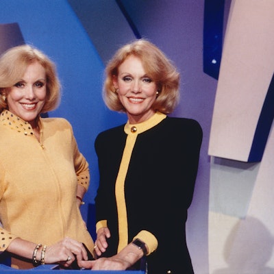 Die Kessler-Zwillinge stehen in einer TV-Kulisse.